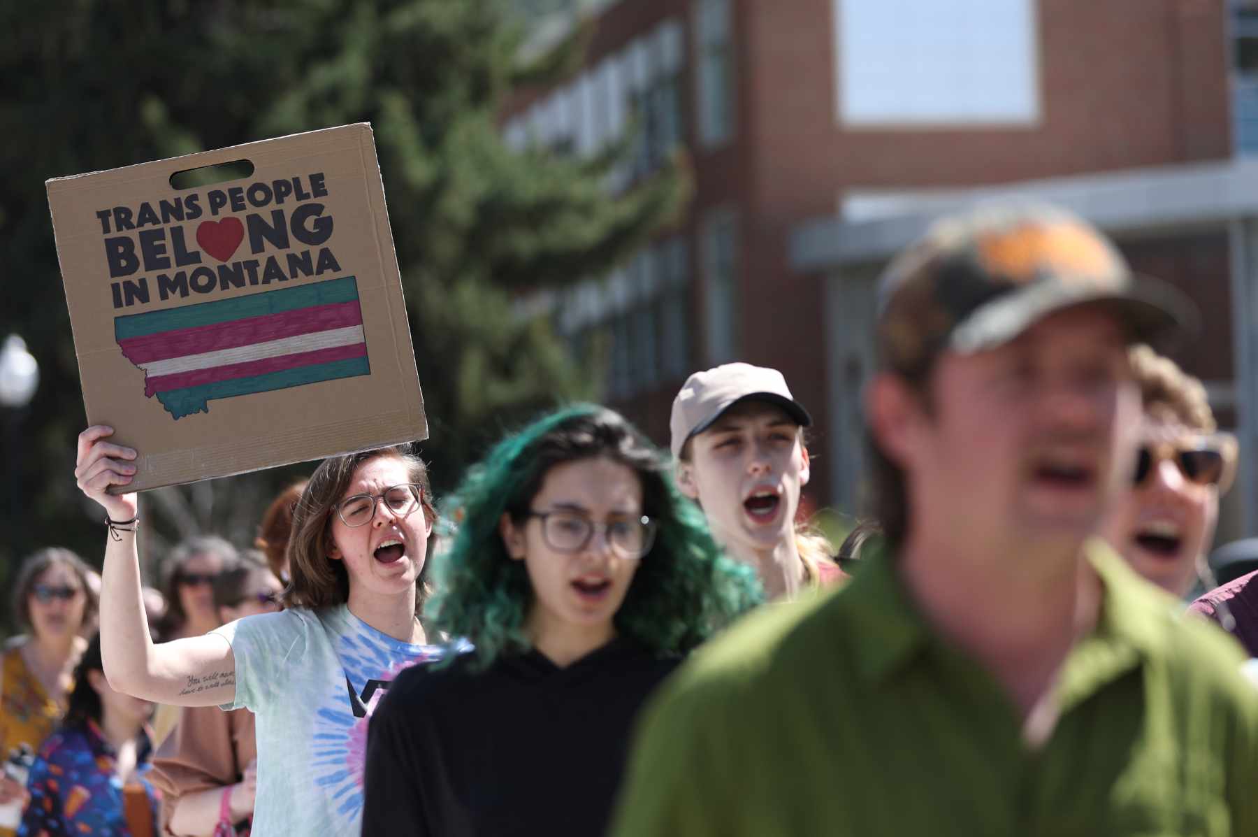 Transgender rights activists i march through the University of Montana campus on May 03, 2023 in Missoula. One holds a sign saying, "trans people belong in Montana."