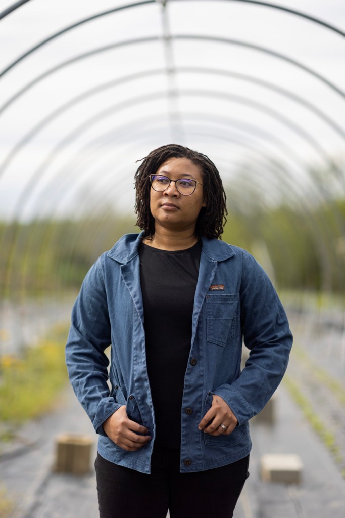 A woman farmer stands in her greenhouse.