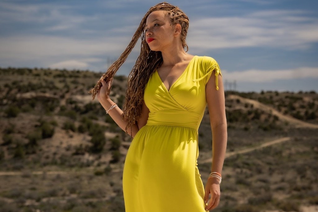 A portrait of a woman against a barren landscape backdrop.