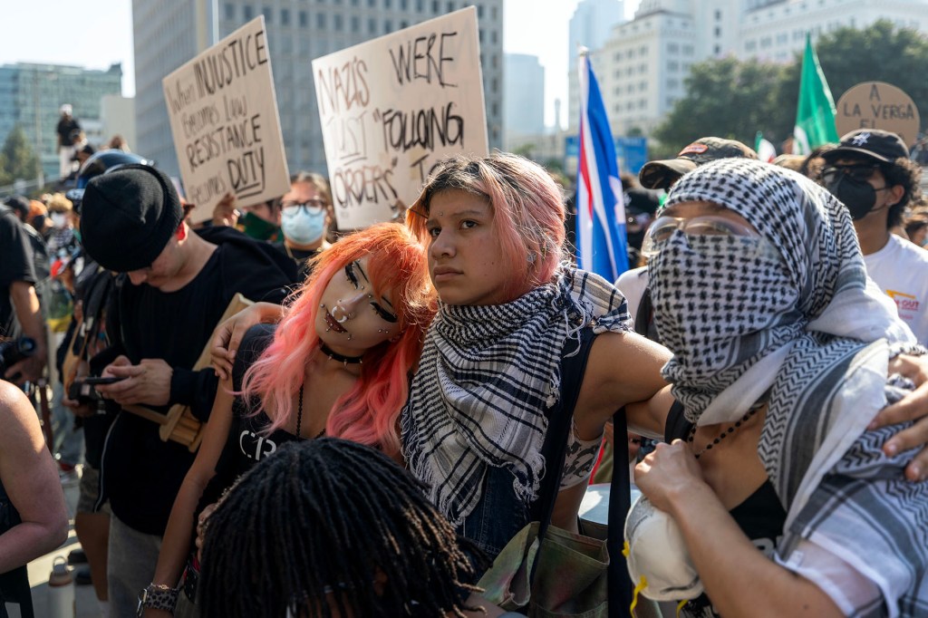 Protesters hold each other as people confront California National Guard and police outside of a federal building in Los Angeles.