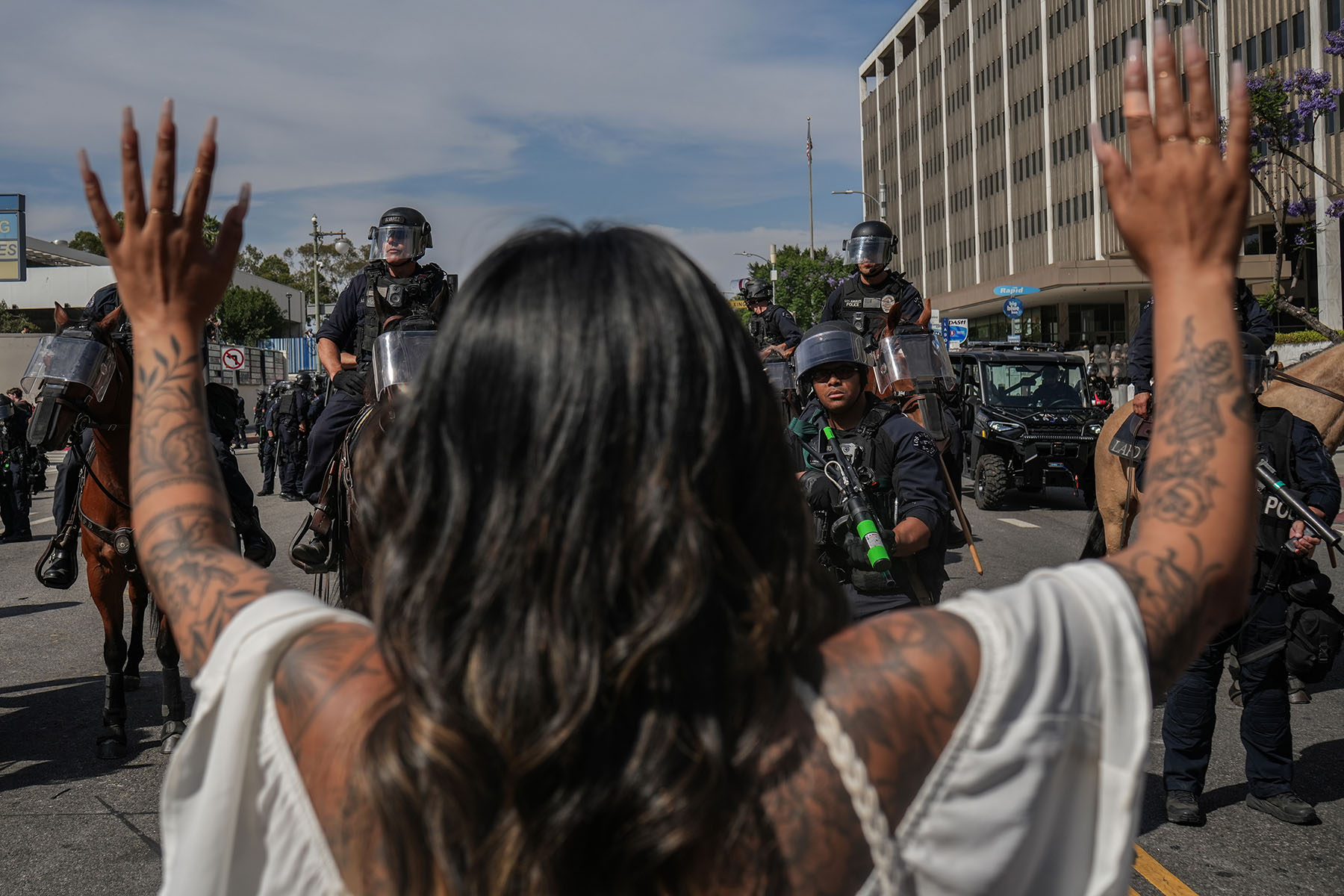 A woman raises her hands in front of Los Angeles Mounted Police officers during the No Kings Day protests taking place across the nation.