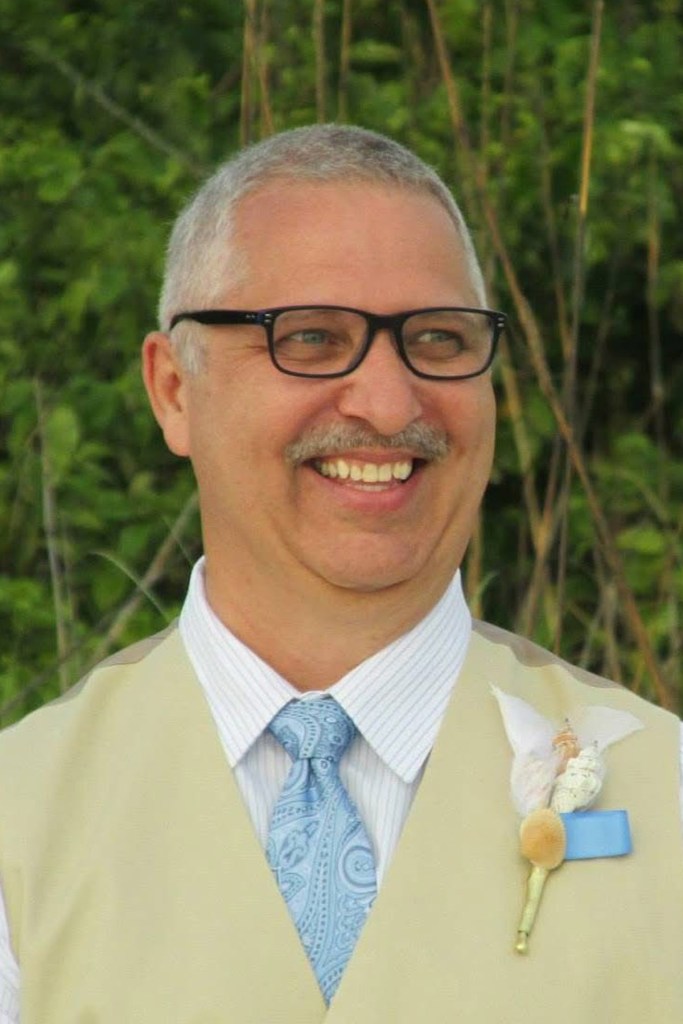 A man wearing a suit smiles.