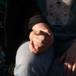A mother holds her non-binary child's hand.