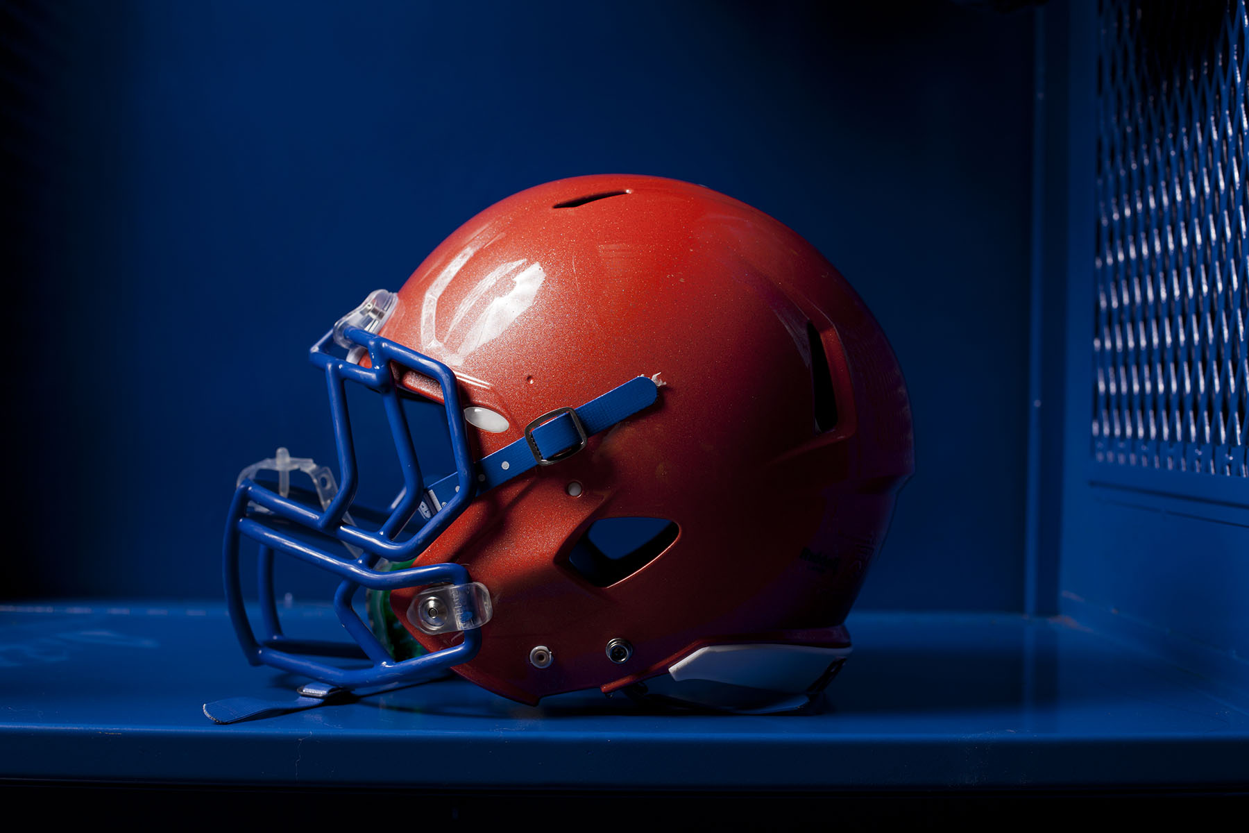 An american football helmet sits in an empty locker.