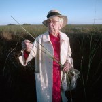Marjory Stoneman Douglas, author and champion of the preservation of the Florida Everglades examines a grass stalk.