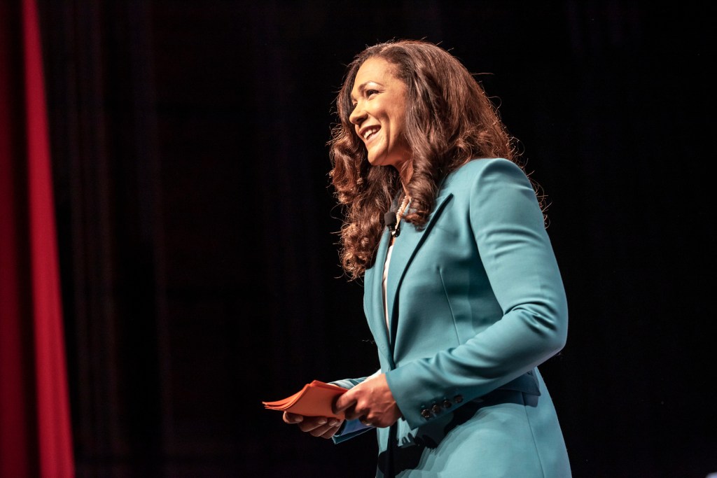 A woman smiles on stage.