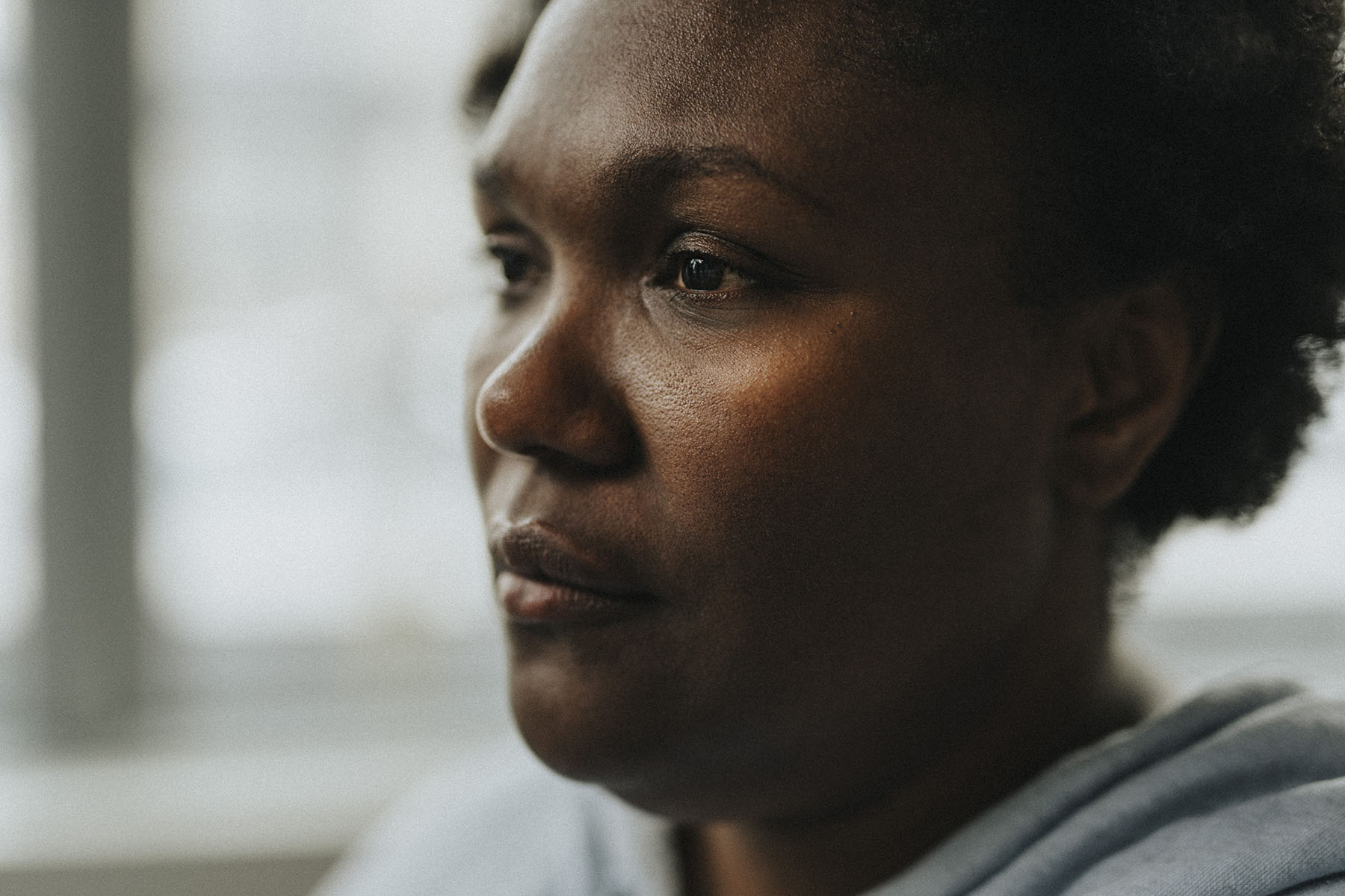 A black woman stares into the distance with a strong expression on her face.