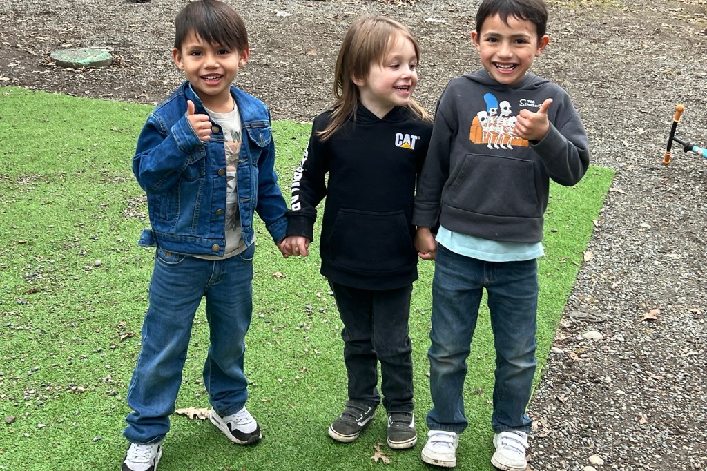 Three young children pose for a photo.