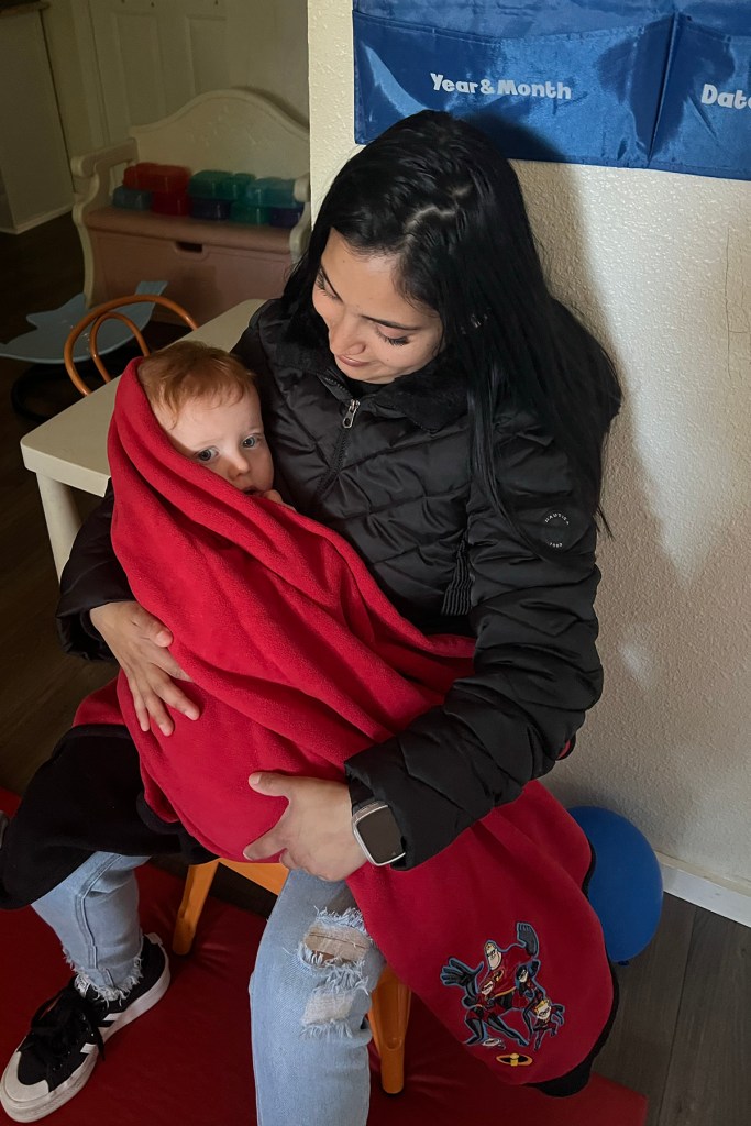 A woman holds a baby in her lap.