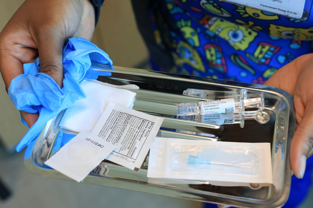 An immunization nurse carries a tray with a COVID-19 vaccine at Borinquen Health Care Center.