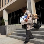 A Department of Education employee leaves the building with their belongings.
