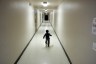 A toddler runs down a stark hallway.