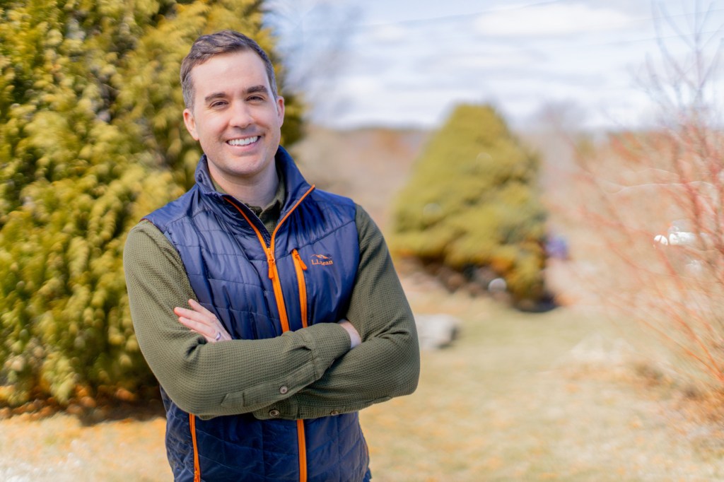 Jordan Wood smiles at camera against a wilderness backdrop.