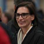 A woman smiles in a crowd.
