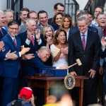 President Donald Trump, joined by Republican lawmakers, holds a gavel after signing the 