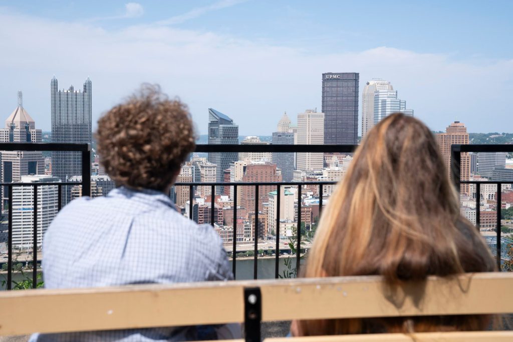 Lee and Nicole look out toward the Pittsburgh skyline from a bench.