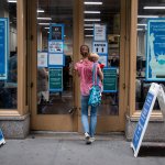 A woman holding an infant walks into a COVID vaccine clinic.