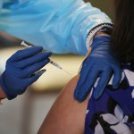 A healthcare worker administers a COVID-19 vaccine to a woman.