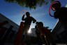 Children play at a playground silhouetted against the sun above them.