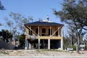 Construction workers stand on the roof of a house under construction.