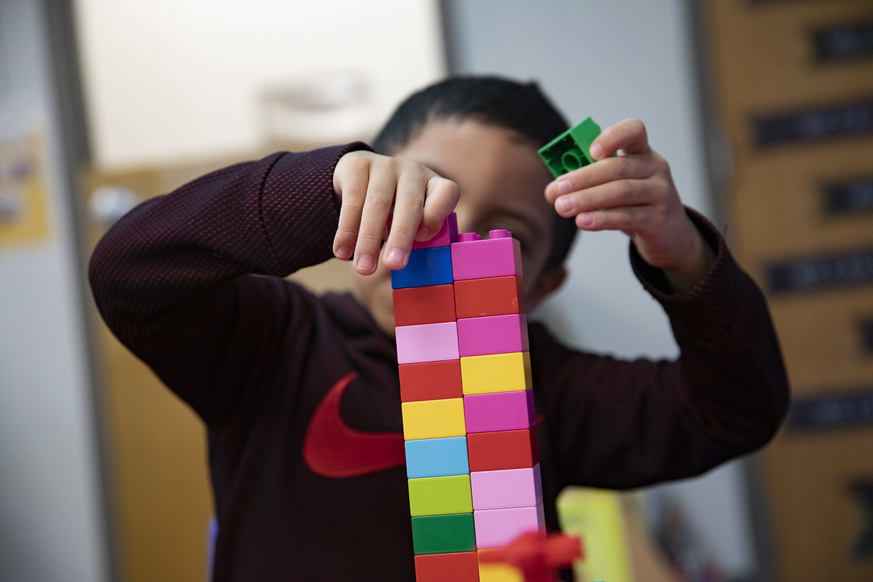 A child makes a tower with colorful Lego blocks.