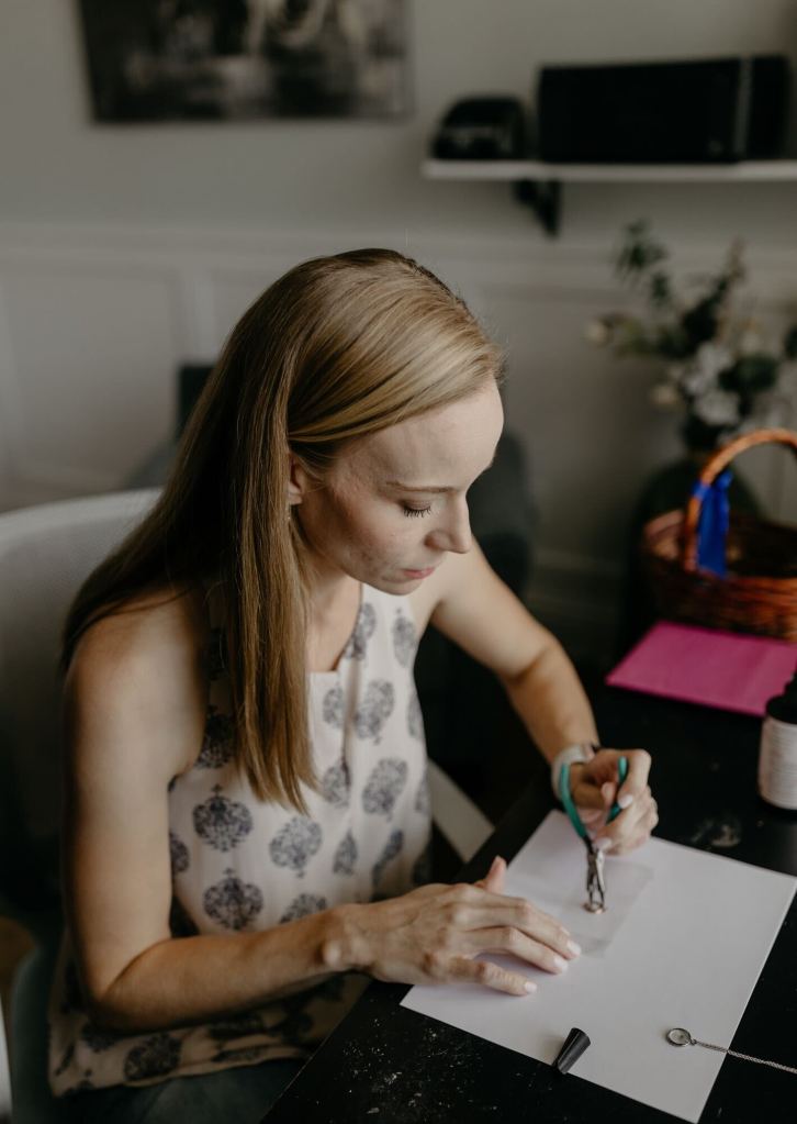 Kellie Abernathy uses pliers to work on a piece of jewelry at her desk, preparing items for her Etsy shop.