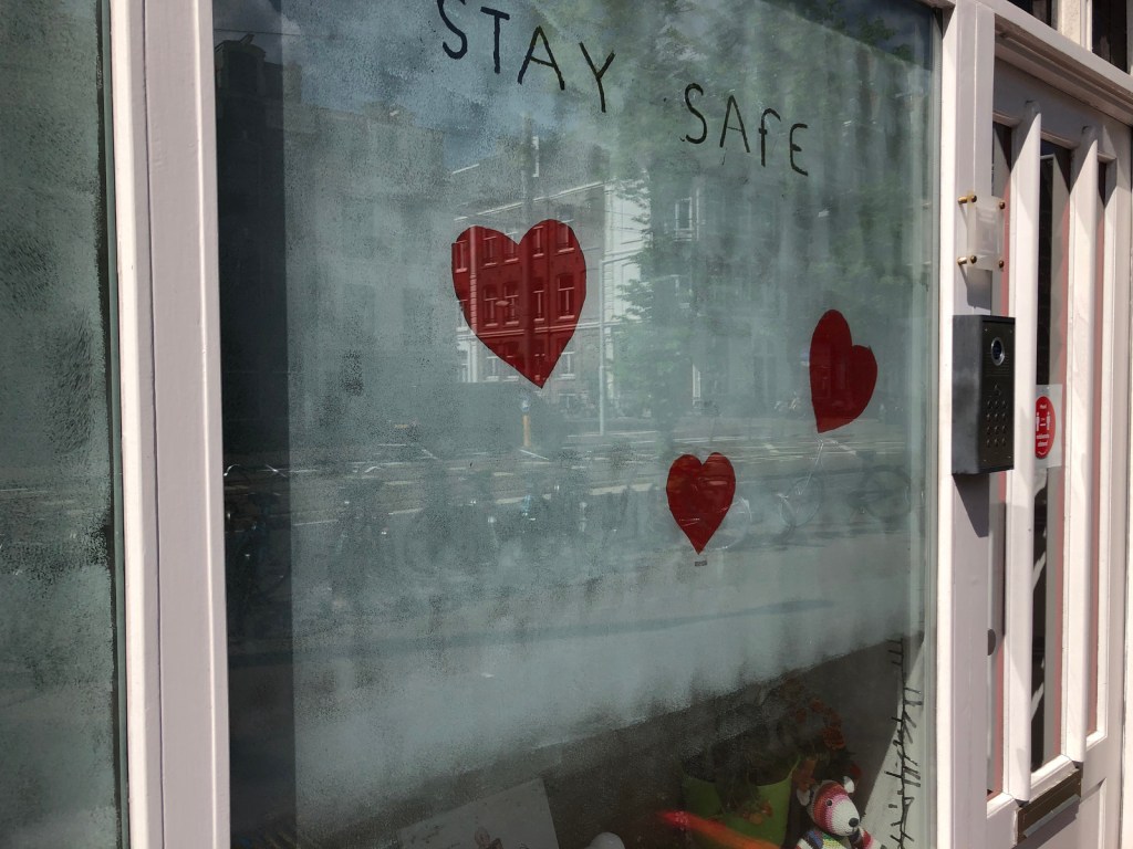 A sign in a window of a daycare re has two hearts and says "stay safe"