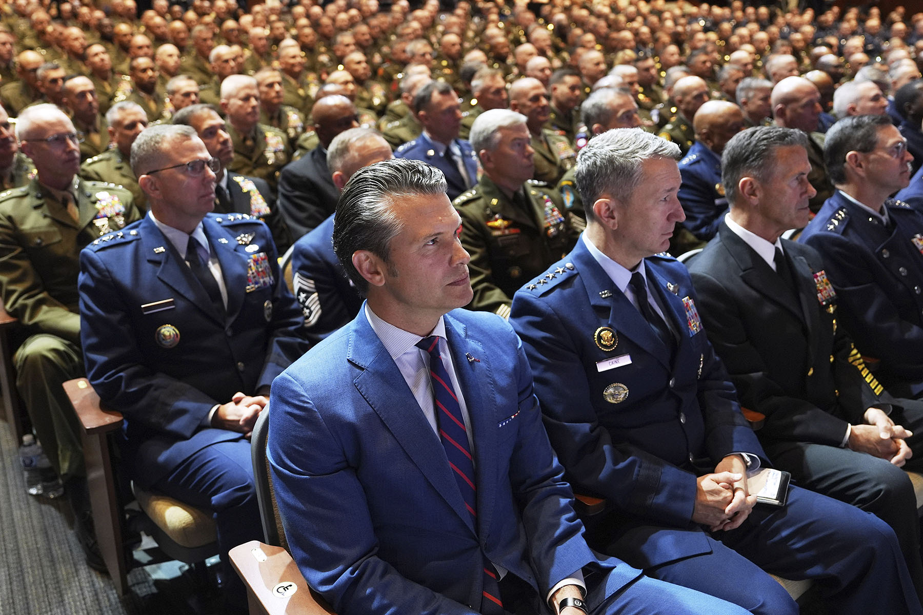 Defense Secretary Pete Hegseth sits with Chairman of the Joint Chiefs of Staff Air Force Gen. Dan Caine, third from right, and U.S. military senior leadership as they listen to President Donald Trump speaks at Marine Corps Base Quantico.