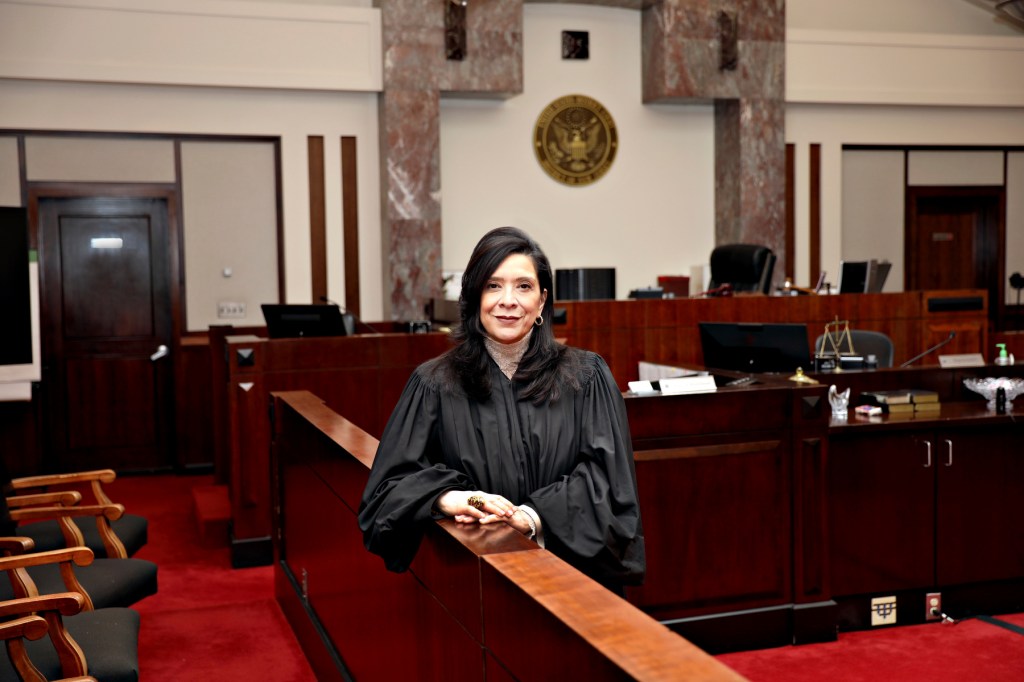 A female judge stands in a courtroom for a portrait.