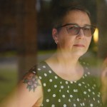 Portrait of Angela Thompson looking through a window