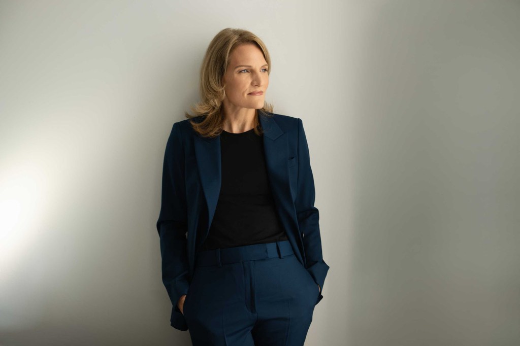 Portrait of the author in a blue suit against a white wall.