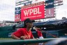 Baseball players stretch on the field with a WPBL billboard in the background.