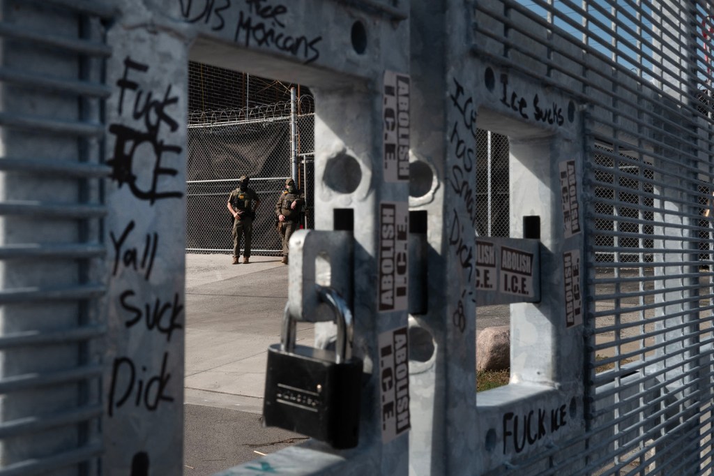 Federal law enforcement agents stand guard near a temporary fence installed outside of an immigrant processing and detention center.