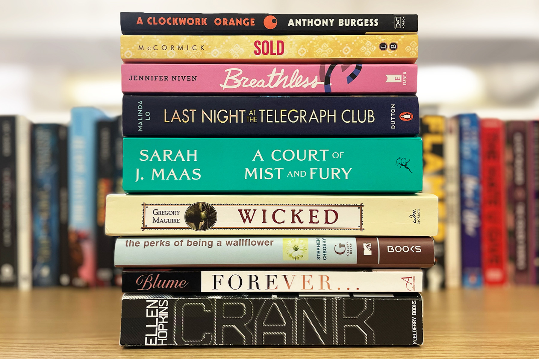 A closeup on a tower of banned books with other books in the background.