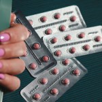 Photo of silver colored blister packs with small pink pills.