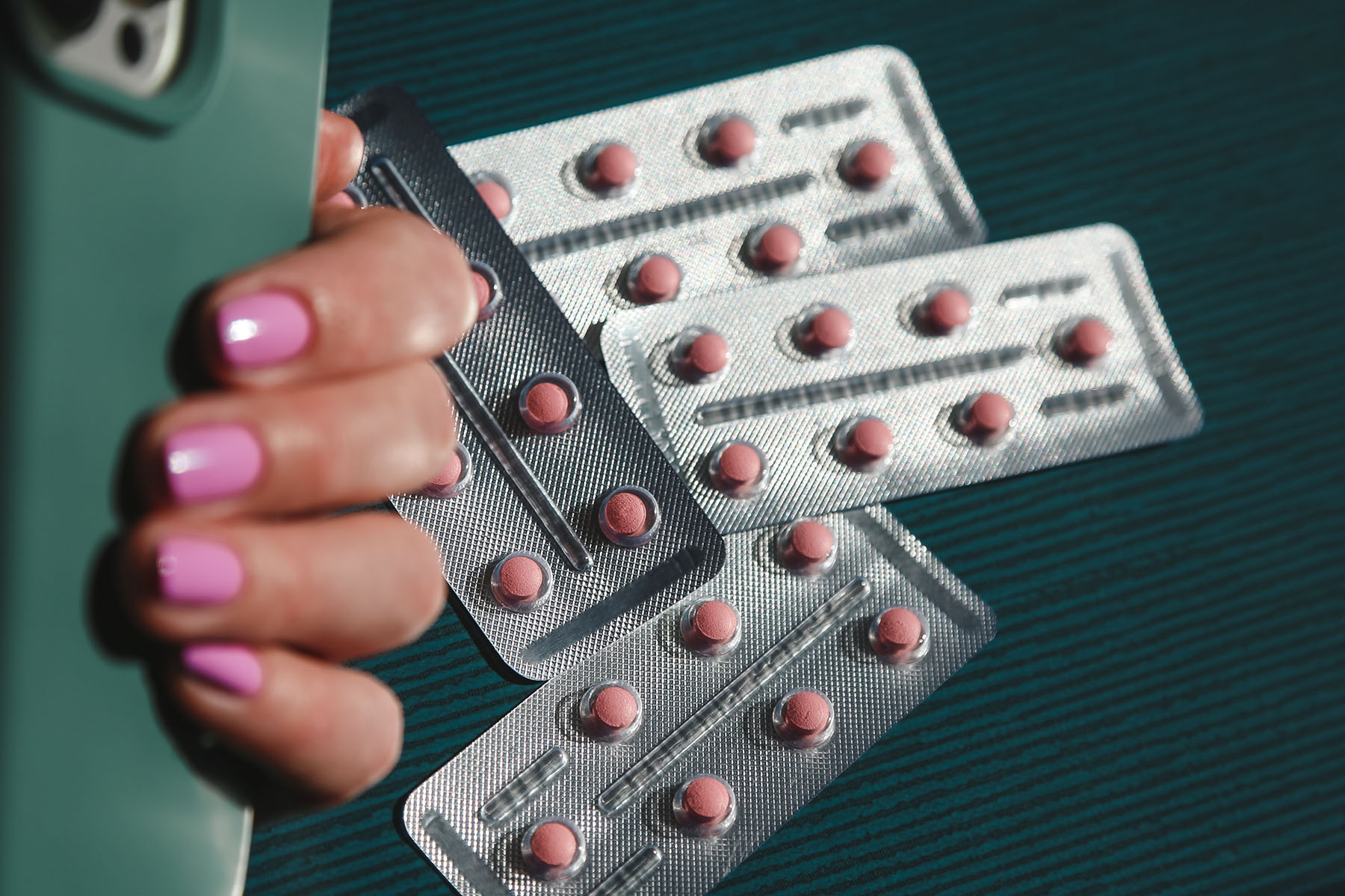 Photo of silver colored blister packs with small pink pills.