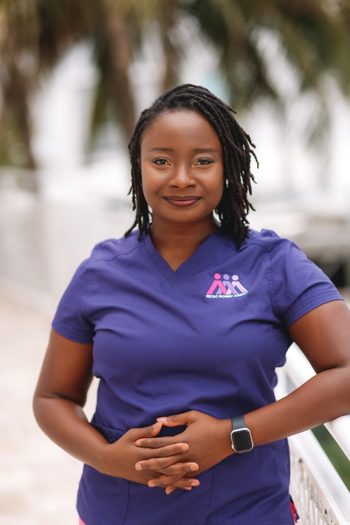 A portrait of Esther Louis standing in scrubs.