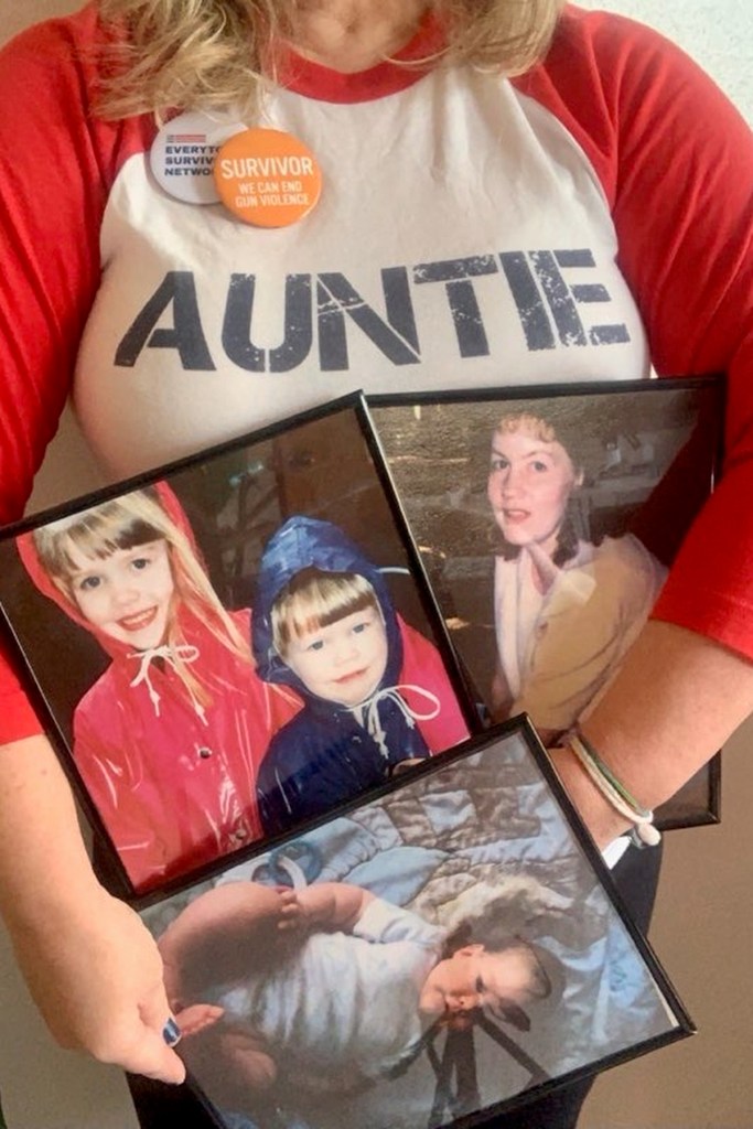 A woman holds framed photographs of another woman and three young children in her arms.