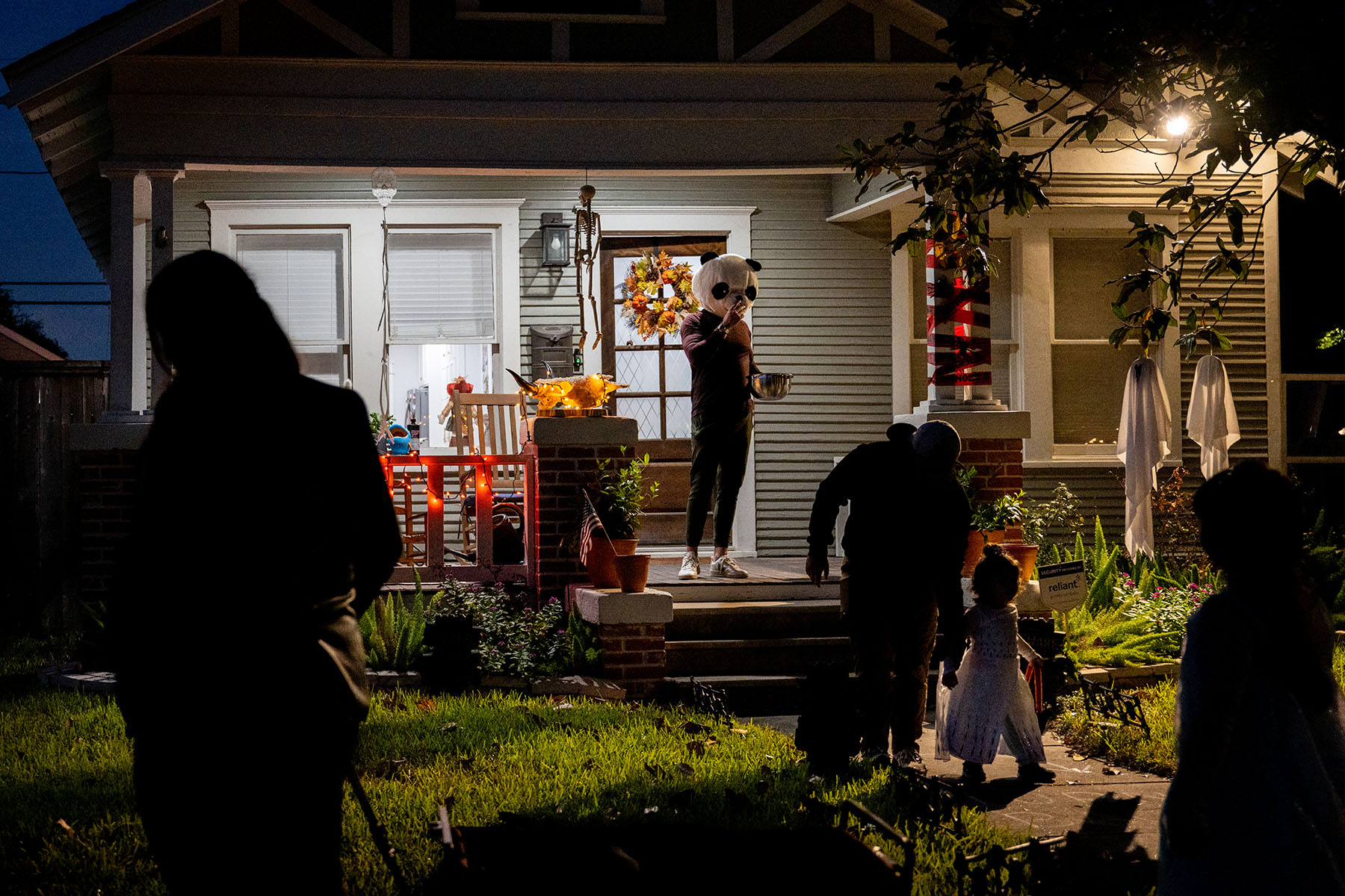 Trick-or-treaters are seen leaving a house in costume.