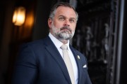 Cory Mills stands in a doorway in a suit.