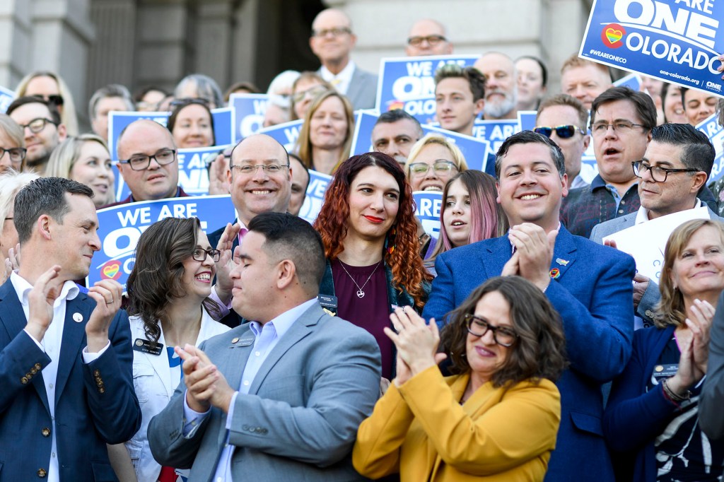 Lawmakers applaud during the signing of the bill that bans the use of conversion therapy on minors in Colorado.