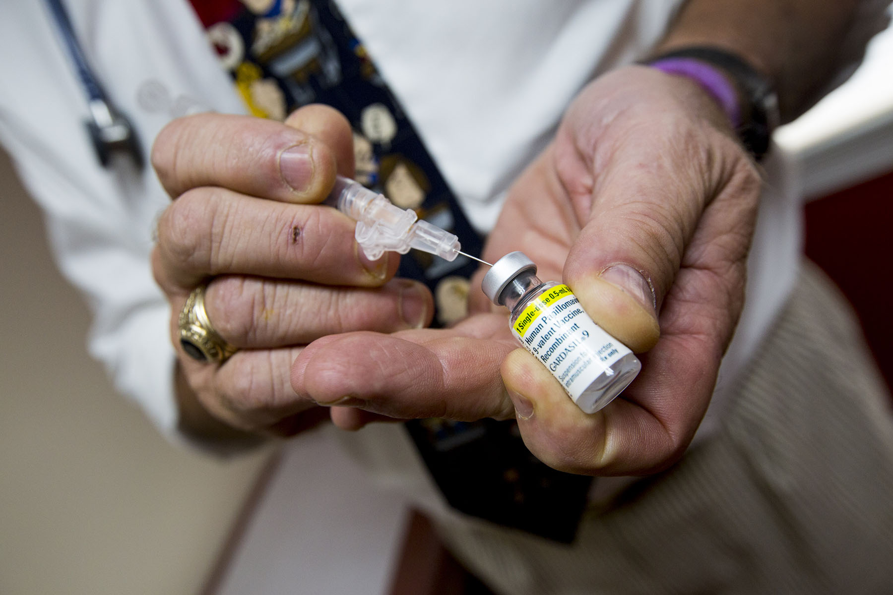 A doctor prepares a shot of the HPV vaccine for a patient at his office.
