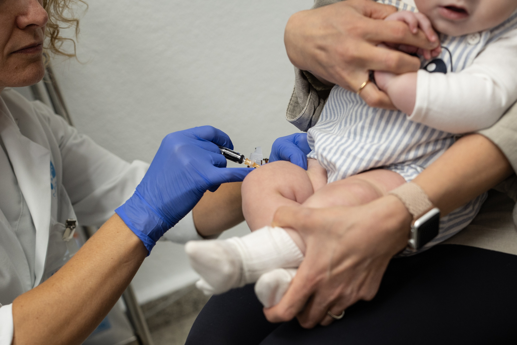 A doctor gives a baby a vaccine while a parent holds the baby in their arms.