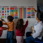 Claudia Pellecer plays games with children in the living room of her home daycare.