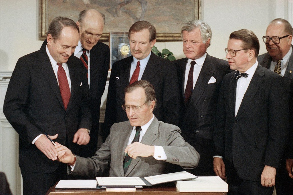 President George H. Bush hands a pen to Attorney General Dick Thornburgh (left) after he signed The Immigration Act of 1990 into law.