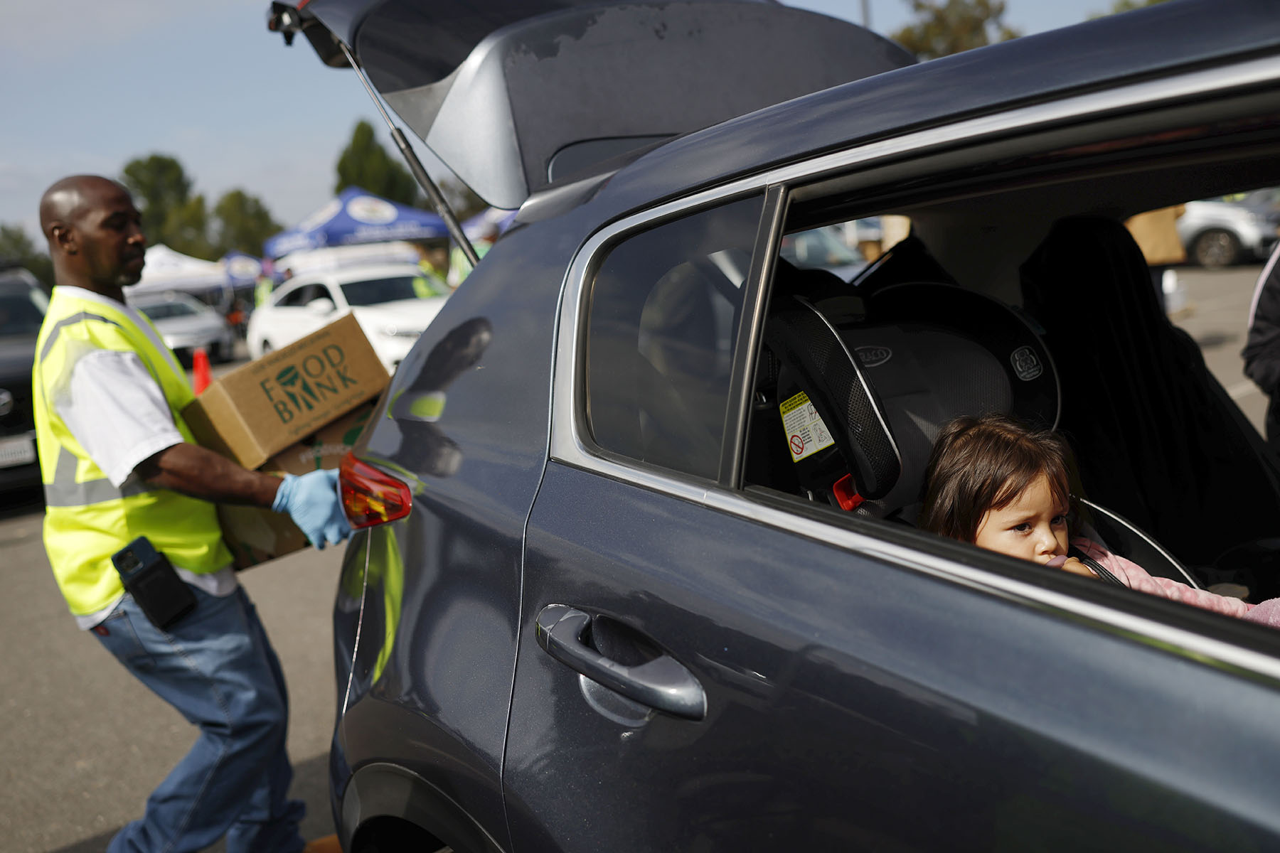 A volunteer distributes food boxes to a family at a large-scale drive-through food distribution, in response to the federal government shutdown.