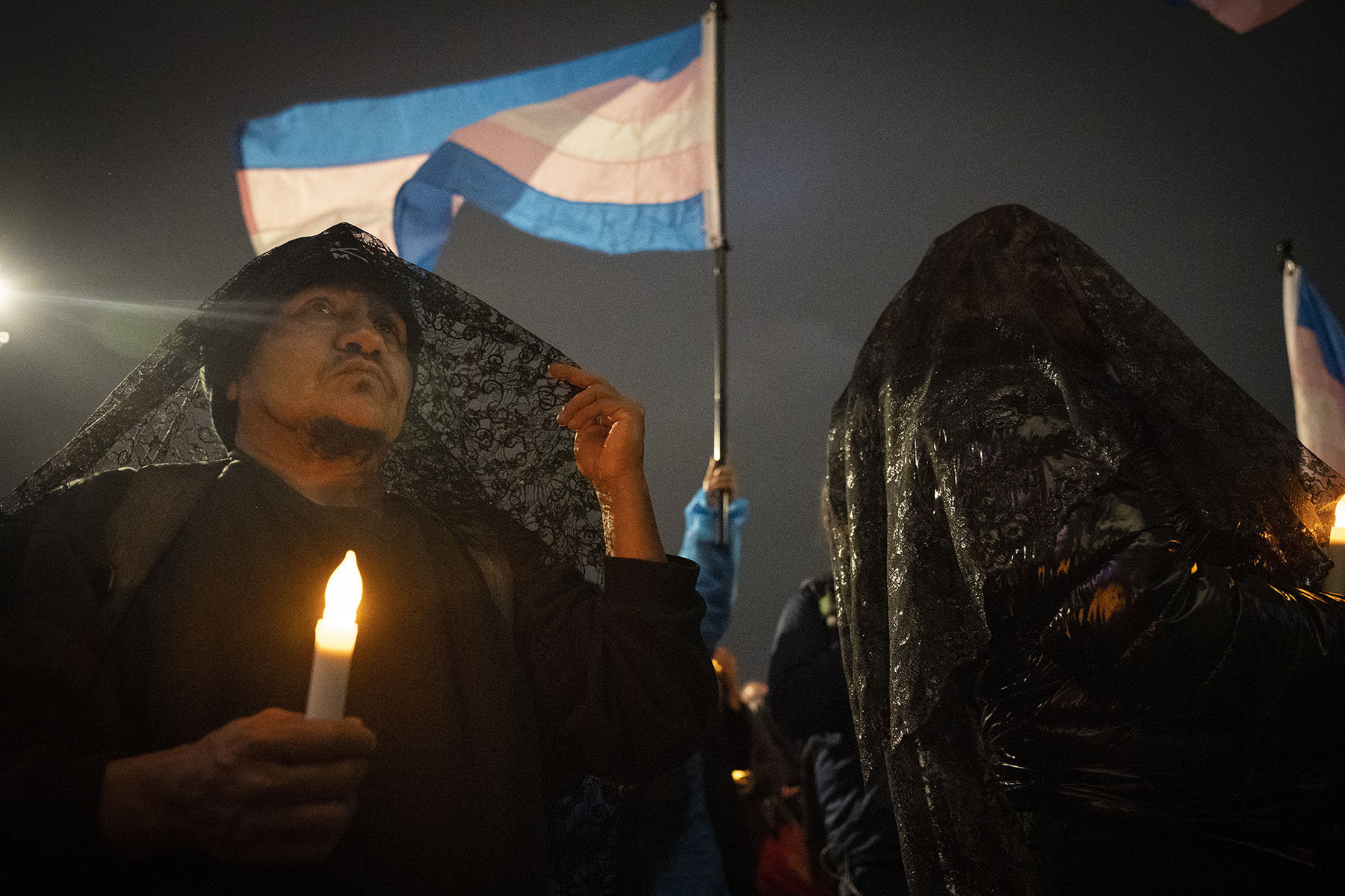 People wearing dark capes attend a vigil to commemorate Transgender Day of Remembrance in San Francisco.