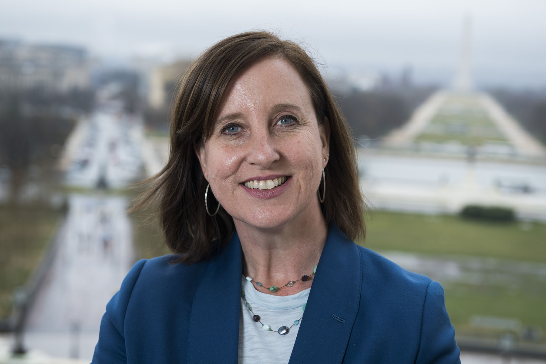 Terri McCullough is photographed at the Capitol. She is wearing a blue jacket and smiles as she looks at the camera.