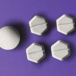 Several abortion pills on a purple background.