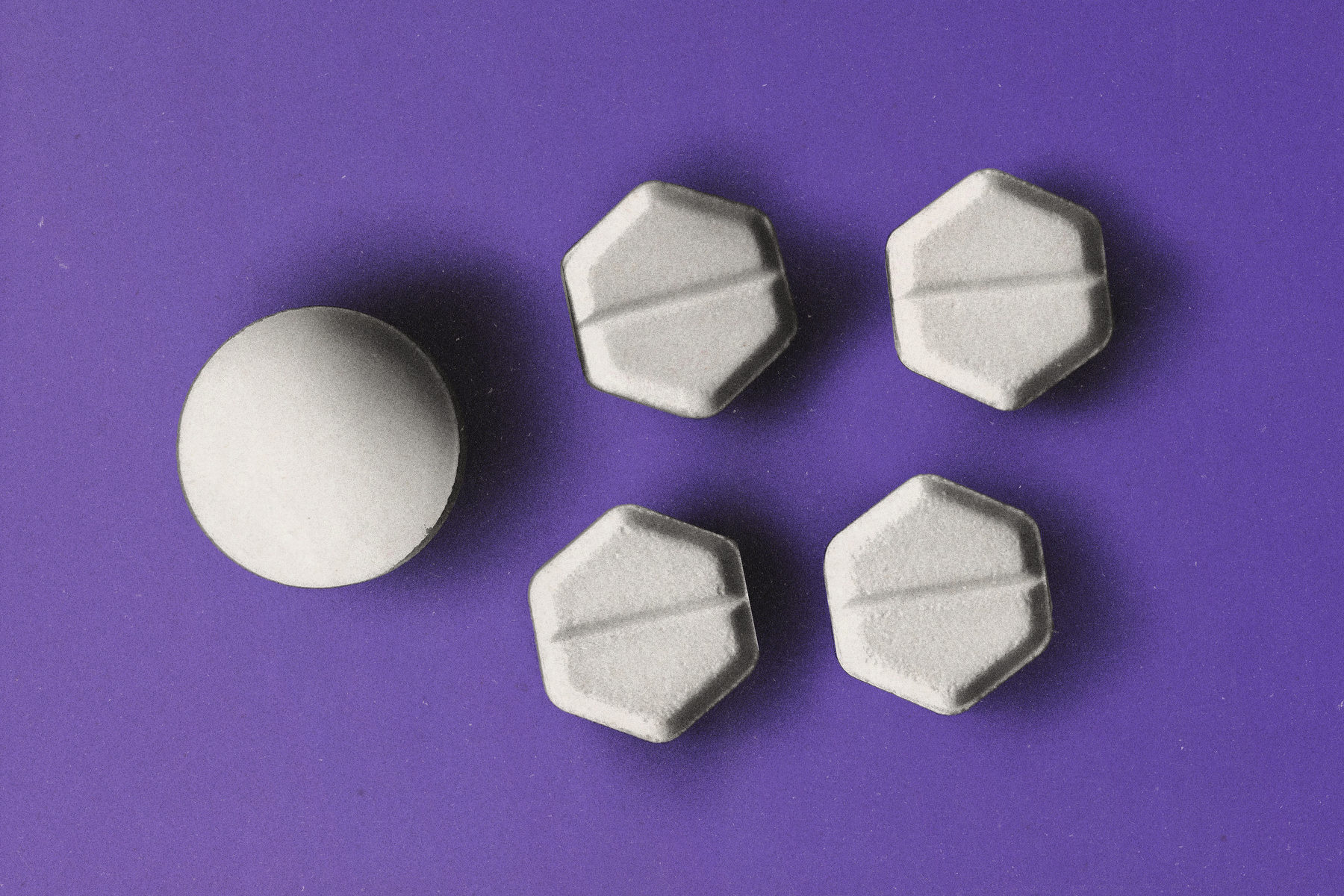 Several abortion pills on a purple background.